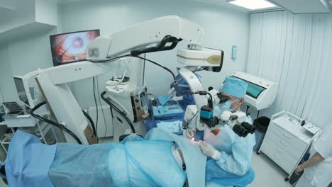 surgeon looking into the microscope at the eye of female patient at the operating room. doctor using microscope during eye surgery process, treatment of cataract and diopter correction.