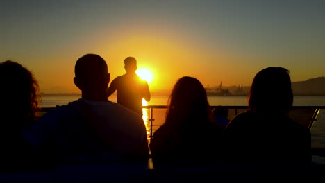 silhouetted people watching a mesmerizing sunset over the sea, creating a peaceful and reflective atmosphere, with warm orange hues filling the sky