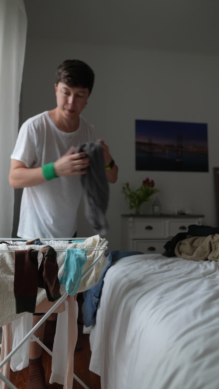 A young man doing laundry in a bedroom