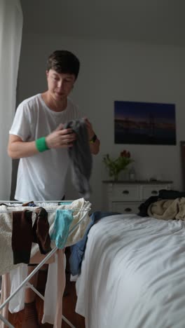 a young man doing laundry in a bedroom