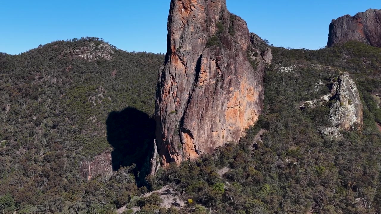 Vidvinkelbilde av fjellformasjonen The Breadknife under klar blå himmel i Warrumbungle nasjonalpark