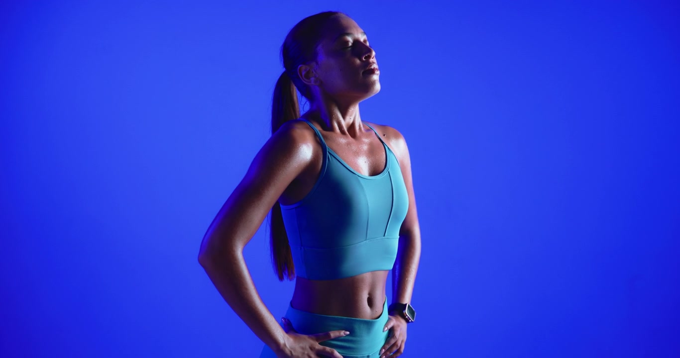 Donna atletica sudata che si riposa dopo l'allenamento su sfondo blu