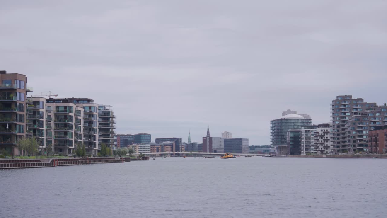 Static shot of wide city canal with waterfront buildings on sides, Copenhagen