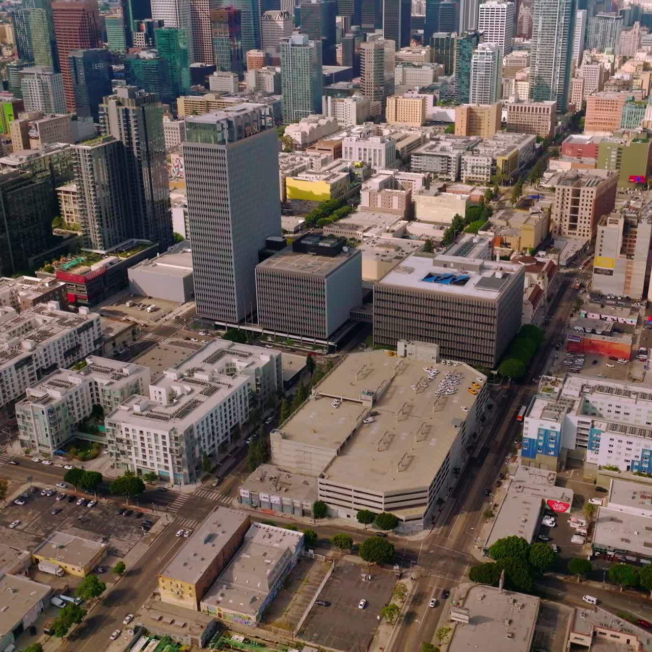 Approaching amazing skyscrapers in the financial downtown Los Angeles, California. Drone footage over the city panorama at backdrop of hills and blue skies