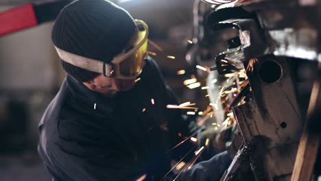 workman with protective eyewear is grinding metal construction with circular saw