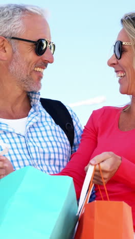 una pareja madura está mirando las bolsas y riendo después de comprar