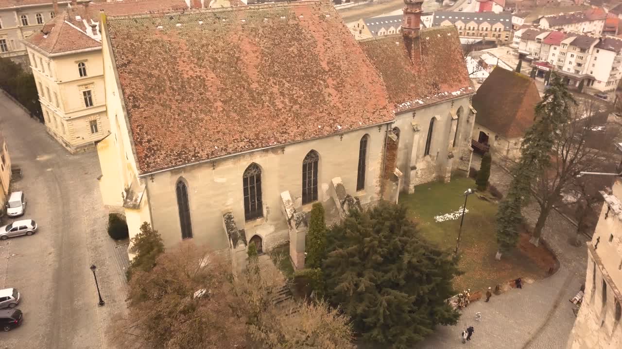 una toma de dron, con movimiento panorámico y de camiones combinados, capturando una propiedad arquitectónica en la ciudad de sighisoara en una tarde