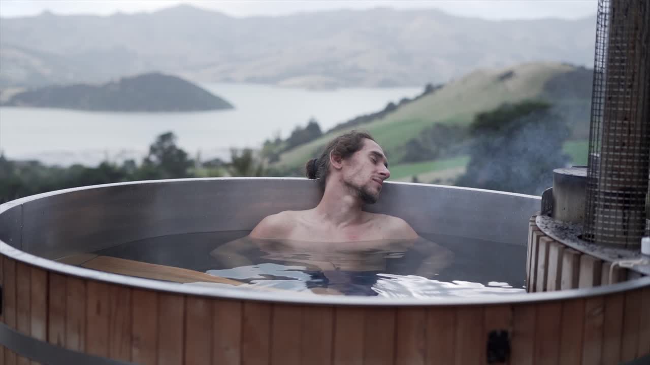 Man relaxing in a hot tub with a scenic view