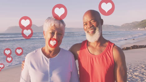 animation of hearts over happy senior african american couple on sunny beach