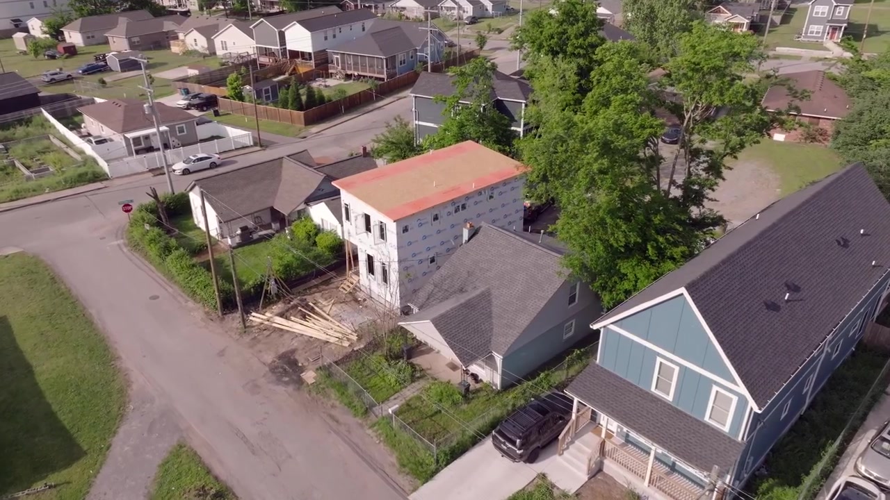 Drohnen-Luftaufnahmen eines halbfertigen Wohnhauses in einem alten Viertel mit Neubauten im modernen, hohen und schlanken Stil