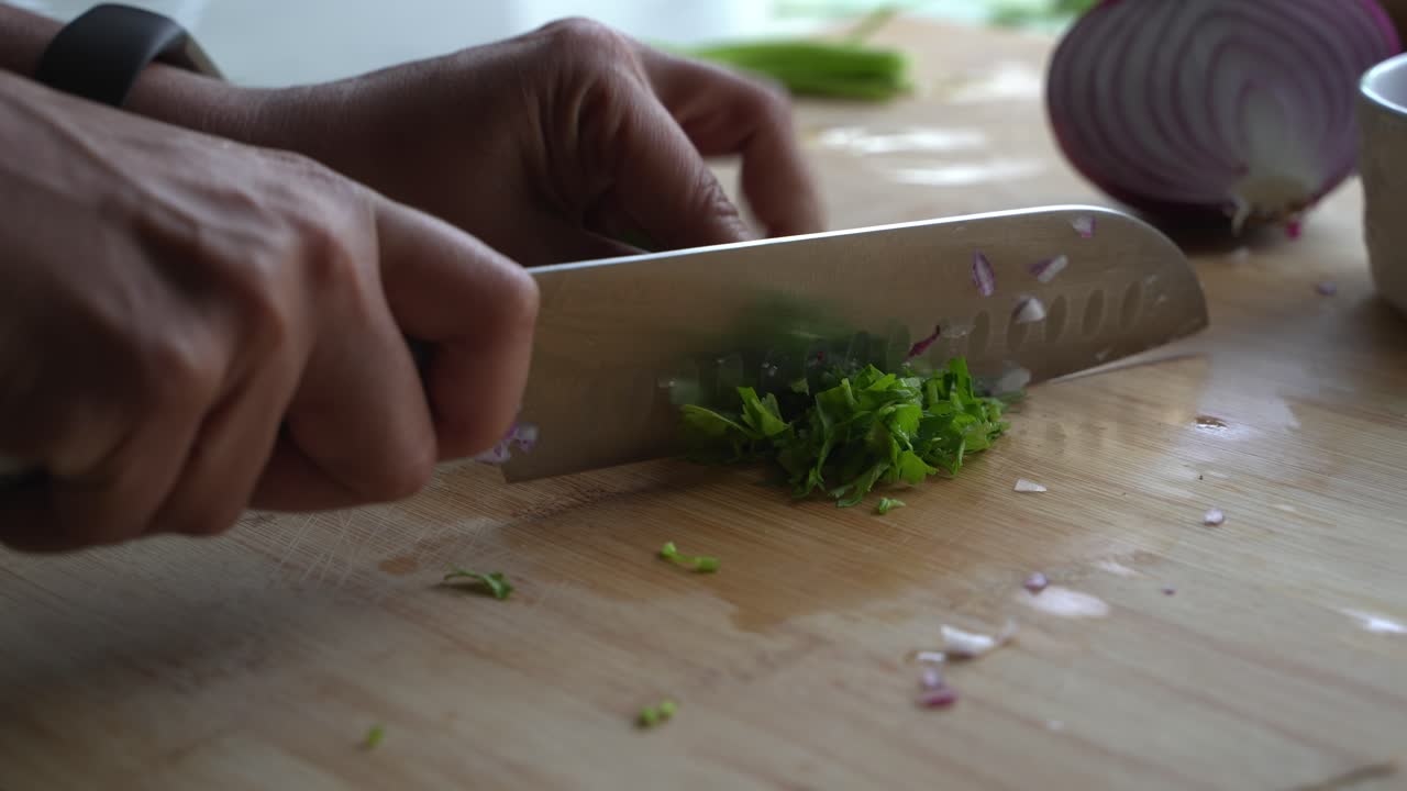 Close up of cutting cilantro into small pieces for garnish and flavor special ingredients to cook a meal two cans of beans rice plantain avocado red onion and cilantro