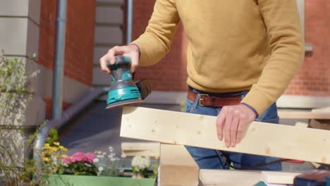 el artesano toma la tabla de madera en la mano y la muele
