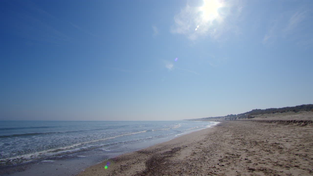 Wide shot looking South down Horsey beach to Winterton on Sea, with sun flare