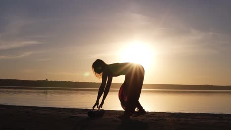 Mujer-Joven-Haciendo-Ejercicio-De-Yoga,-Abriendo-Su-Estera-De-Yoga-Cerca-Del-Mar-O-Del-Océano.-Atardecer-O-Amanecer.-Concepto-De-Salud.-Camara-Lenta.