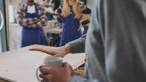 Teacher-With-Hot-Drink-And-Team-Of-Trainees-In-Workshop-Prepare-To-Assemble-Bicycle-Frame