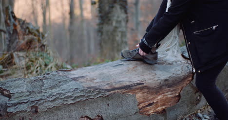 Woman-Tying-Shoe-On-Tree-Trunk