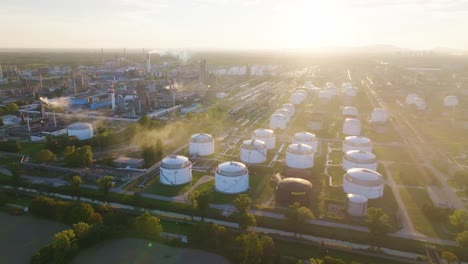 aerial shot of a large industrial refinery and its storage tanks, captured at sunrise