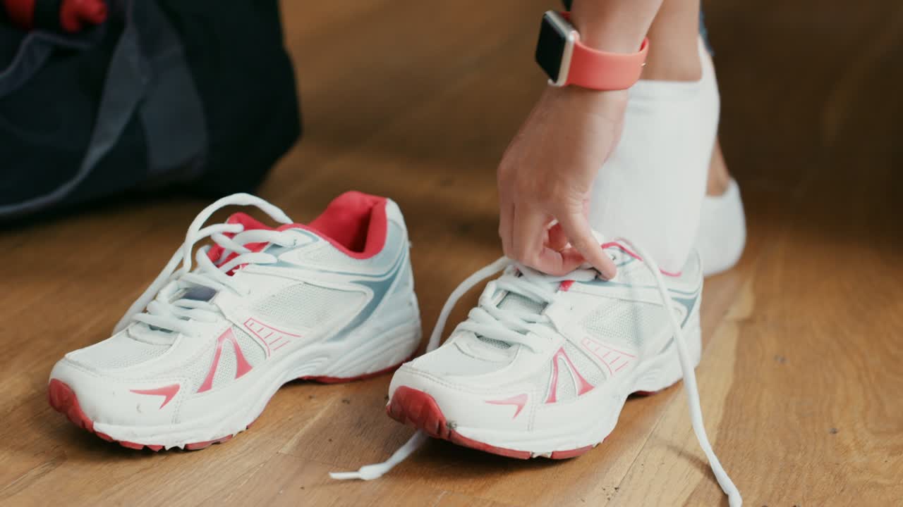 filmato in 4k di una donna che si lega i lacci delle scarpe a casa in preparazione per un allenamento