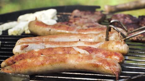 turning meat and sausages on the grill for a tasty outdoor barbecue