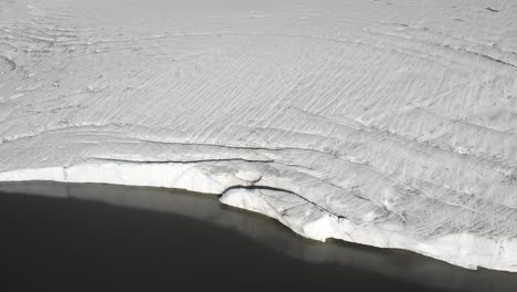 aerial view over the glacial lake and ice of the claridenfirn glacier in uri, swizerland on a calm, peaceful morning with a panning view from the water towards the alpine peaks