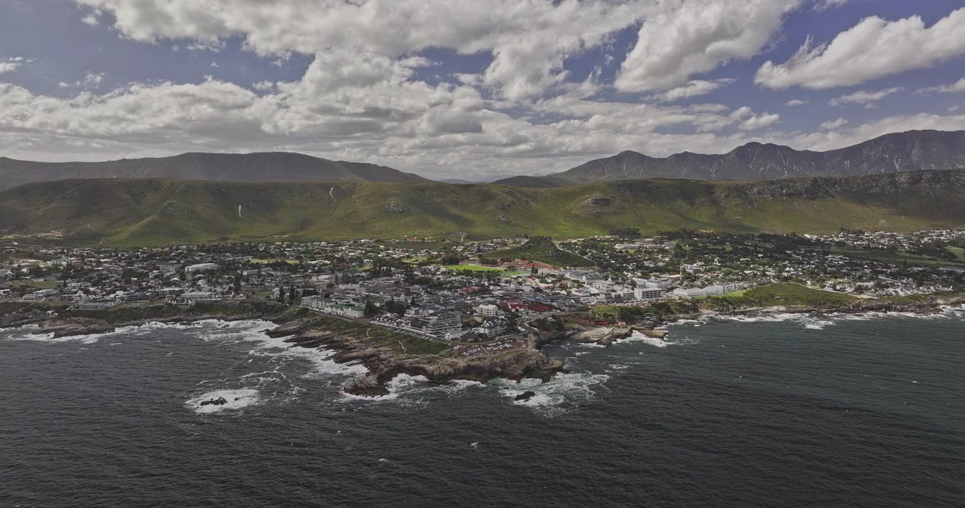 Hermanus Sudafrica. Ripresa aerea v12 con sorvolo inverso alto attraverso la baia verso Gearing's Point, paesaggio urbano sul lungomare e montagne costiere - Ripreso con Mavic 3 Pro Cine - 8 gennaio 2024.