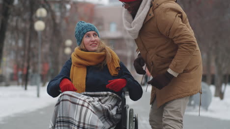 una pareja apoyando a una mujer en silla de ruedas en un día de nieve