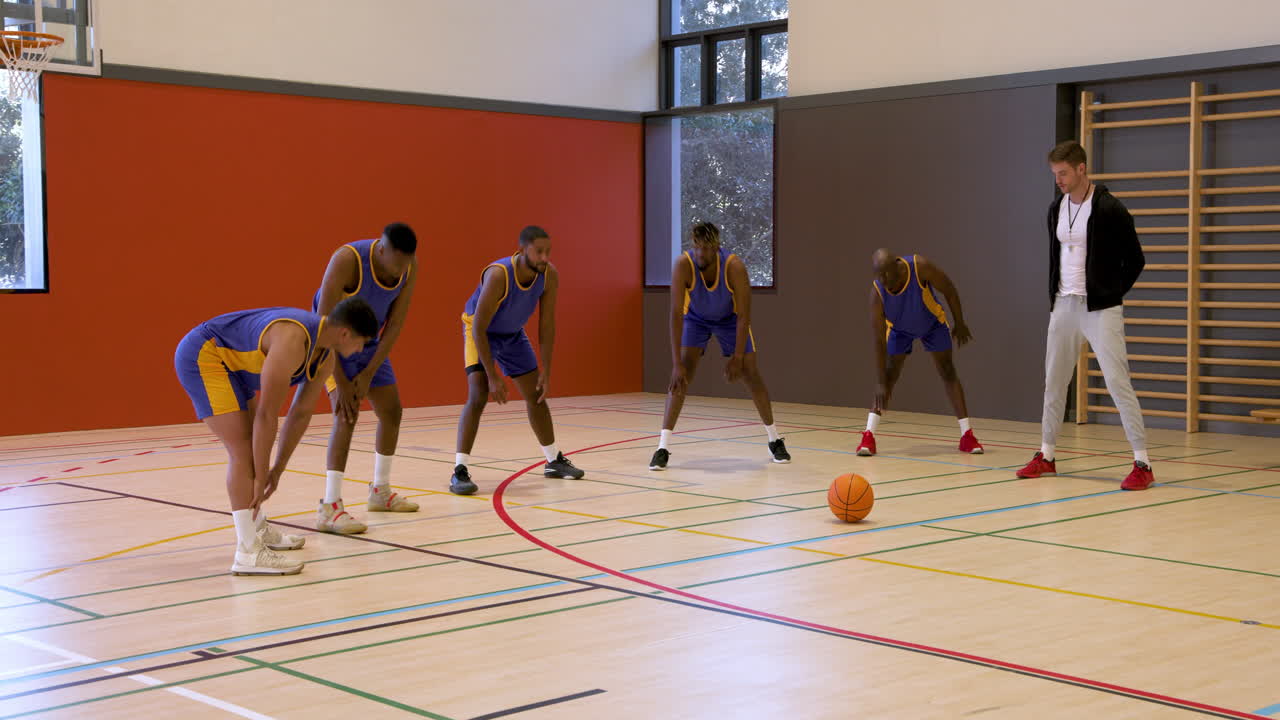 Basketball coach instructing team in gym, players focused on strategy