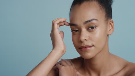 portret aantrekkelijke jonge afro-amerikaanse vrouw met een gladde gezonde huid die er zelfverzekerd uitziet prachtige vrouw die geniet van flirterige sensuele schoonheid op blauwe achtergrond huidverzorgingsconcept