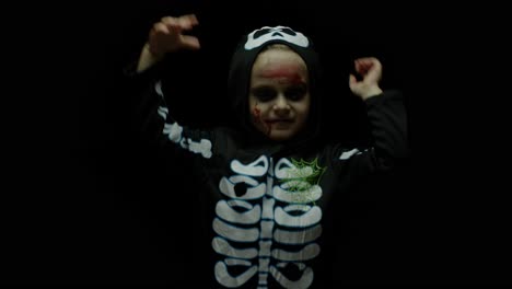 Halloween-angry-girl-with-blood-makeup-on-face.-Kid-dressed-as-scary-skeleton,-dancing,-making-faces