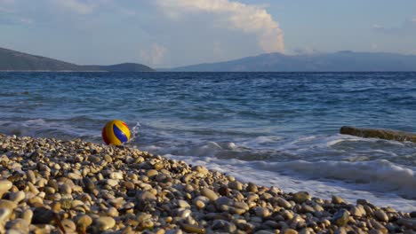 ball playing on sea waves splashing on tranquil beach with pebbles on beautiful coastline of ion