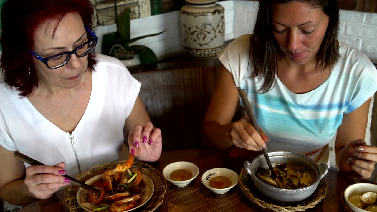 mujeres comen mejillones y camarones en un restaurante japonés