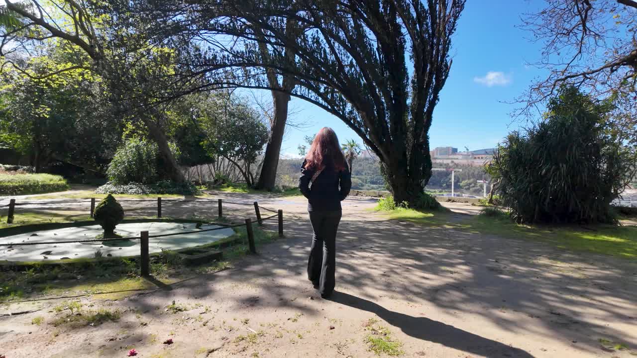Rallentatore di una ragazza che cammina nei Jardins do Palácio di Porto in una giornata di sole.
