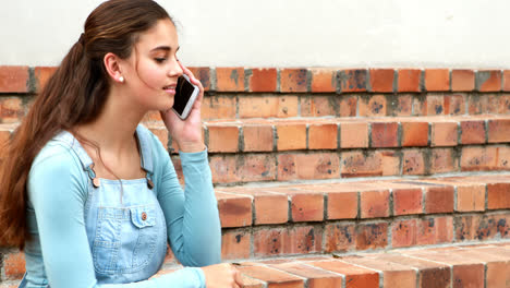 una estudiante feliz hablando por teléfono móvil.