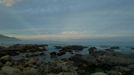 Sun-rays-on-cloudy-day-above-dark-rocks-at-Kaikoura-coast-in-New-Zealand