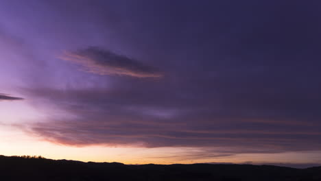 las nubes moradas y azules oscuras brillan con la luz del atardecer en el cielo, lapso de tiempo