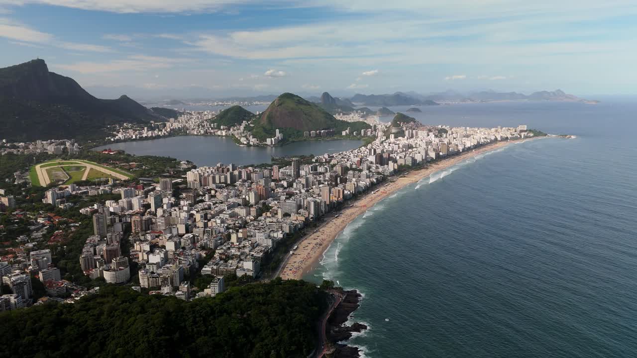 Drone melakukan terbang lintas lambat di atas Rio de Janeiro, menampilkan Praia de Ipanema, gedung pencakar langit kota, perairan laut, dan Lagoa Rodrigo de Freitas