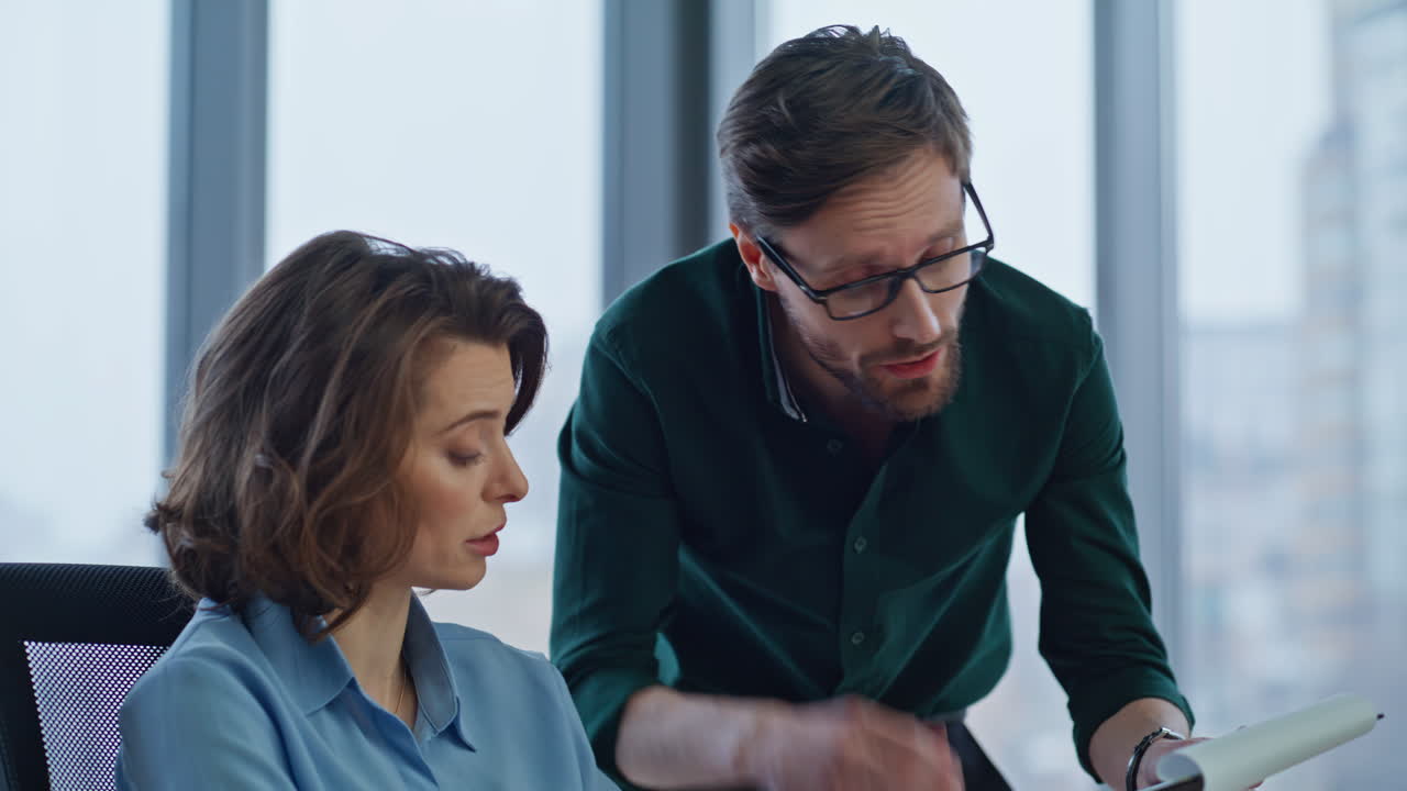 Man supervisor discussing papers with woman manager in corporate office closeup