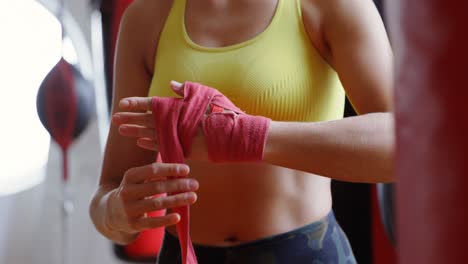 Female-boxer-wearing-hand-wrap-in-fitness-studio-4k