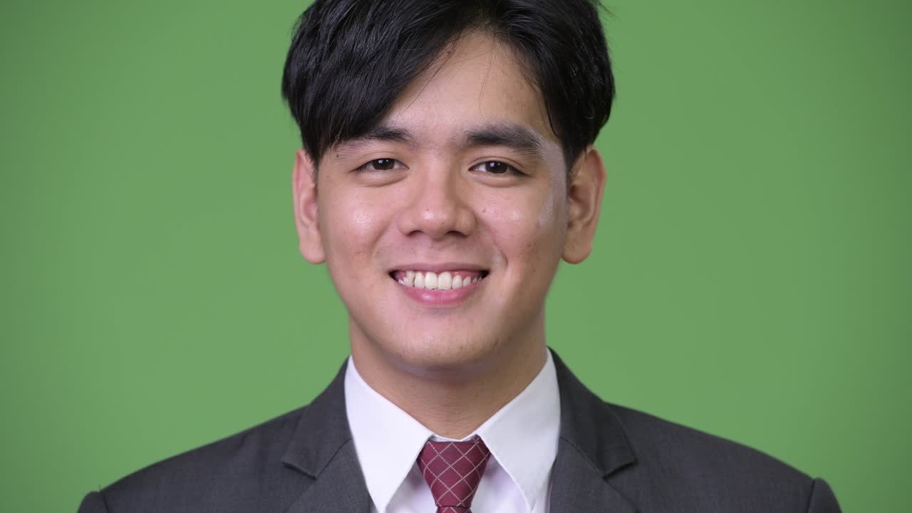 행복한 젊은 잘생긴 아시아 사업가 녹색 배경에 미소