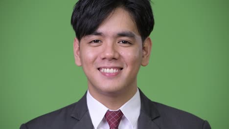 행복한 젊은 잘생긴 아시아 사업가 녹색 배경에 미소