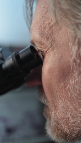 elderly man using a microscope