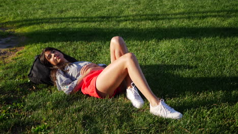 Beautiful-young-hispanic-woman-in-a-daydream-in-a-grass-public-park-field-watching-the-clouds