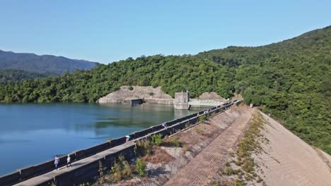 Eine-Dynamische-Luftaufnahme,-Die-Auf-Den-Staudamm-Und-Den-Kontrollturm-Des-Shing-mun-reservoirs-In-Hongkong-Zufliegt