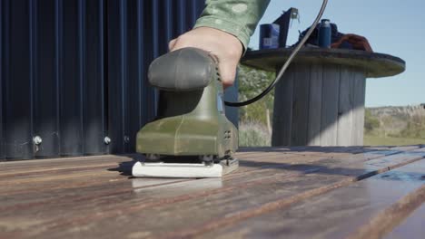 A-man-using-an-orbital-sander,-low-angle-view-in-slow-motion