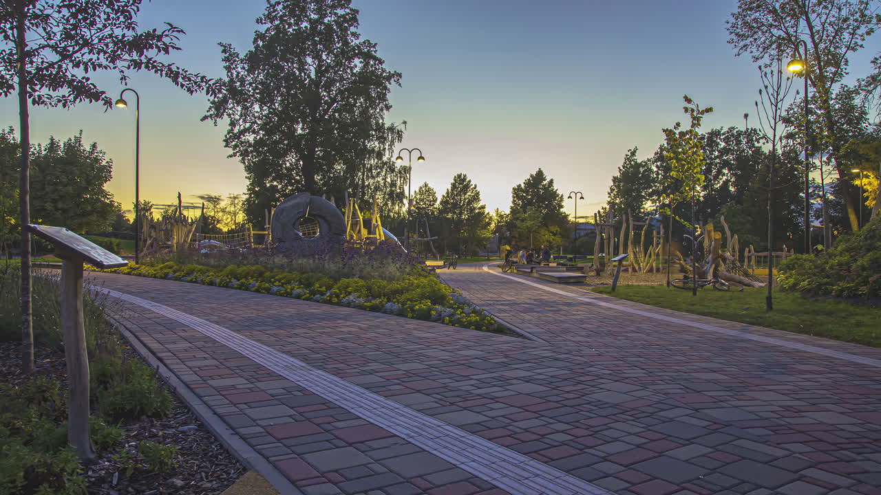 Static shot of a two way pathway among the trees and flower with fresh air in the public tropical garden during evening in timelapse