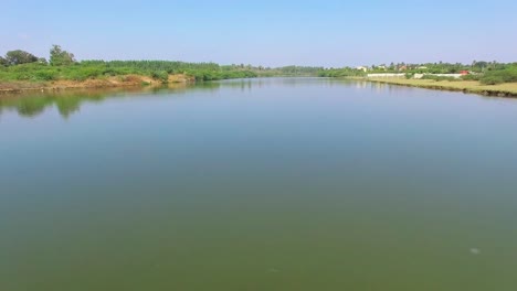 drone shot of flying forwards and upwards across a backwater channel revealing lush green trees on either sides