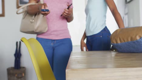 Happy-african-american-mother-and-daughter-entering-house,-leaving-bags-and-keys-on-table