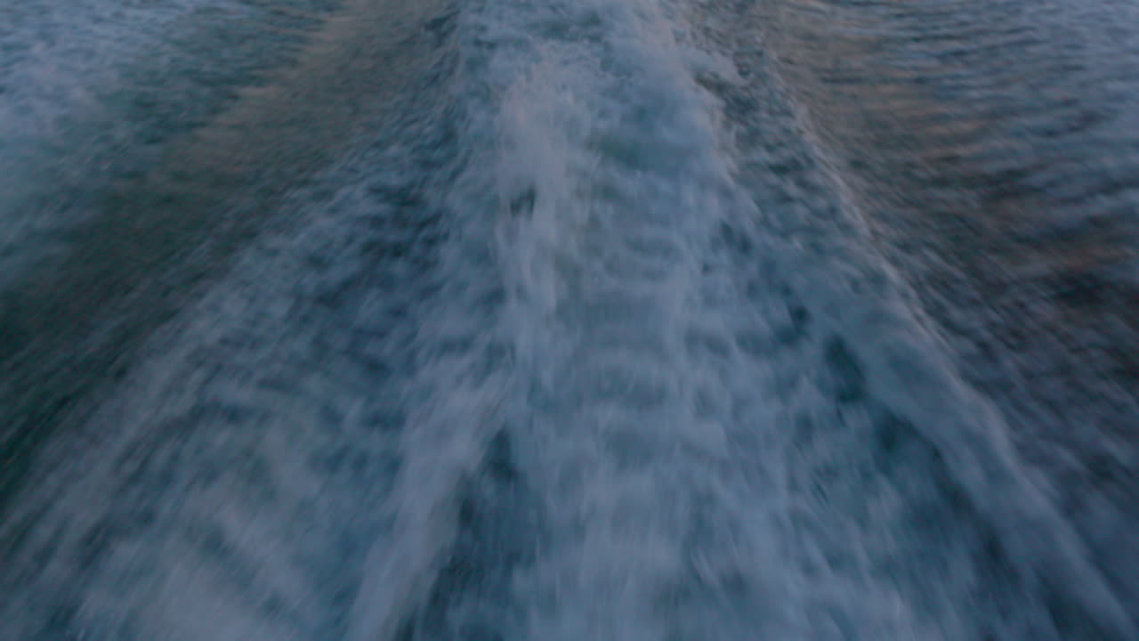 Spruzzi d'acqua dalla scia di un piccolo motoscafo al tramonto.