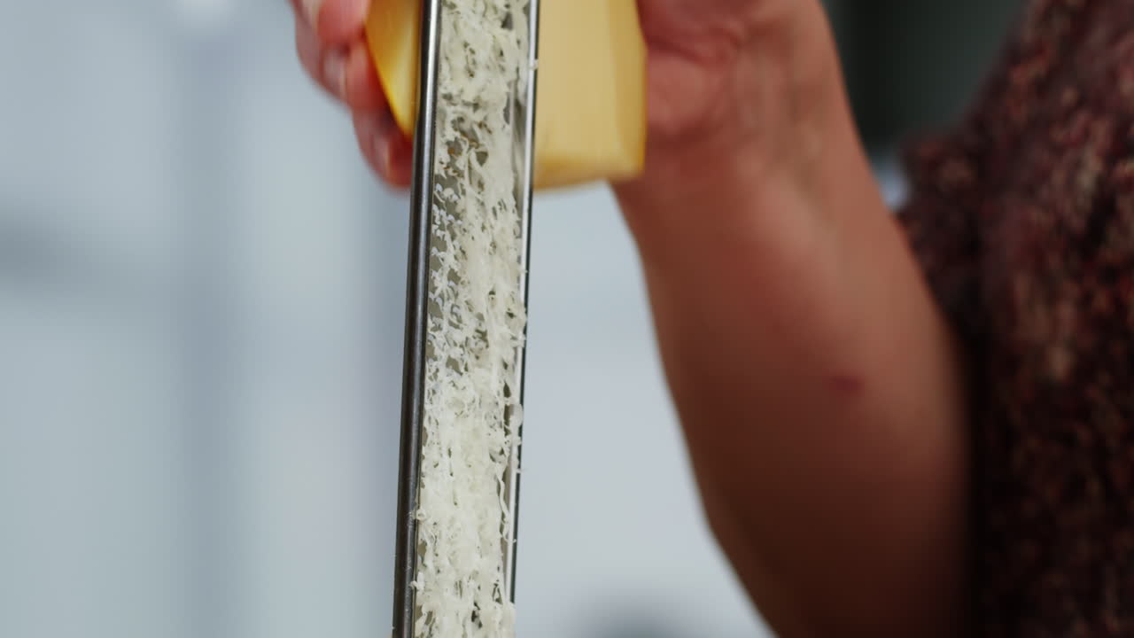 Close-up of Hands Grating Cheese in a Kitchen