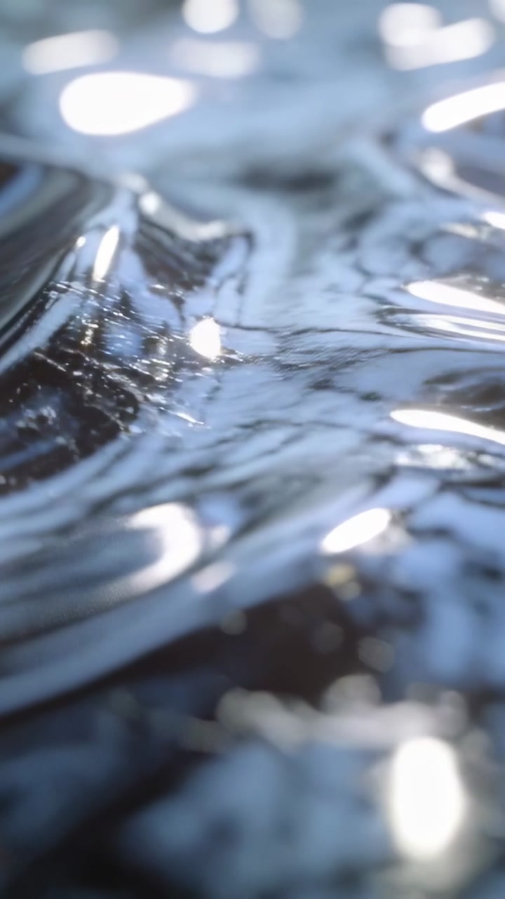 Glossy liquid surface rippling, camera shifting focus and revealing specular highlights for design